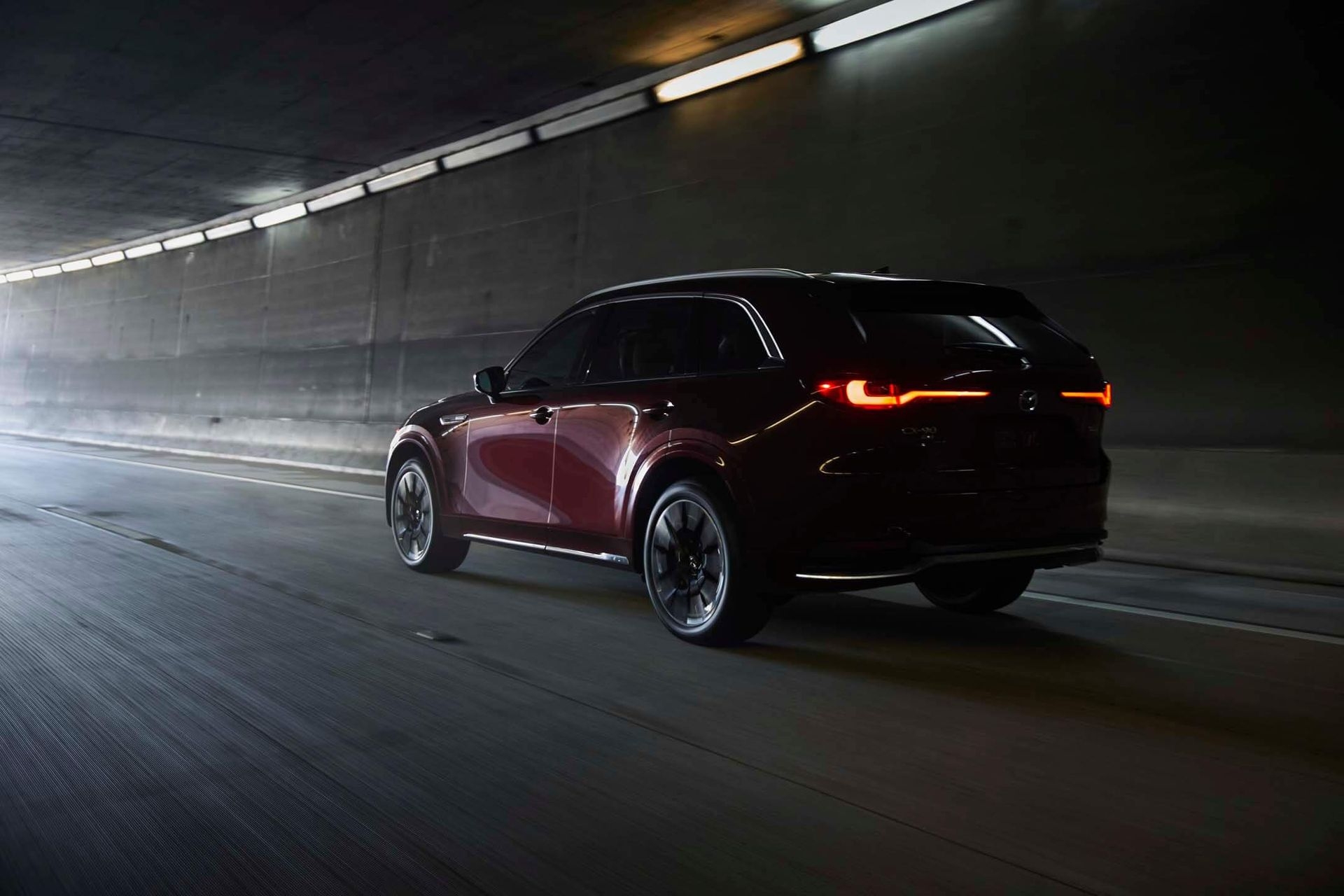 Vue 3/4 arrière du Mazda CX-90 MHEV 2025 roulant dans un tunnel.